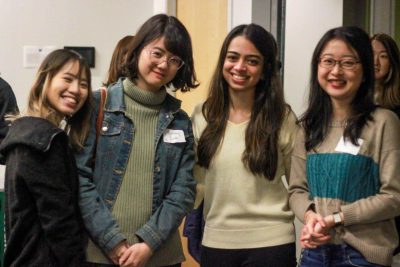 a group of four students stand next to each other smiling