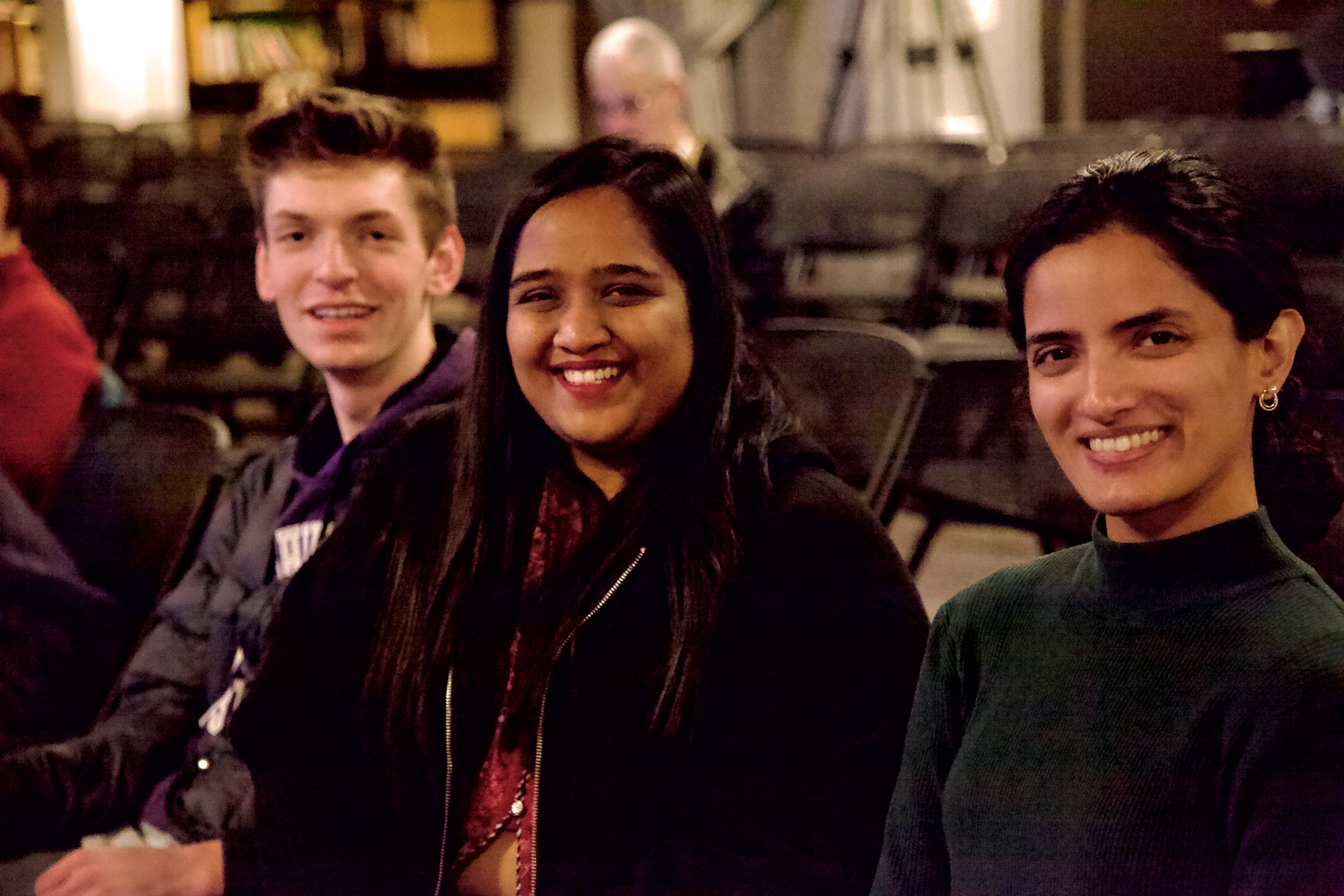 smiling students sit in a row at an indoor venue