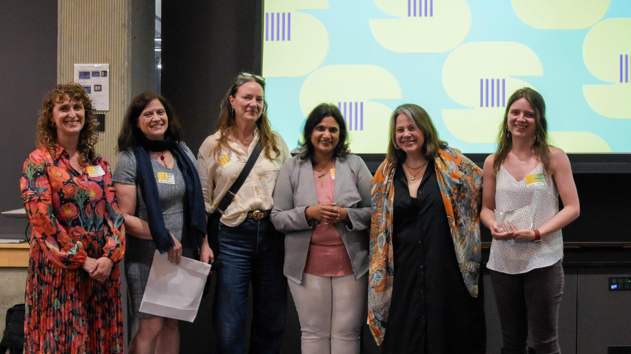 Five women pose for a picture, with one holding an award